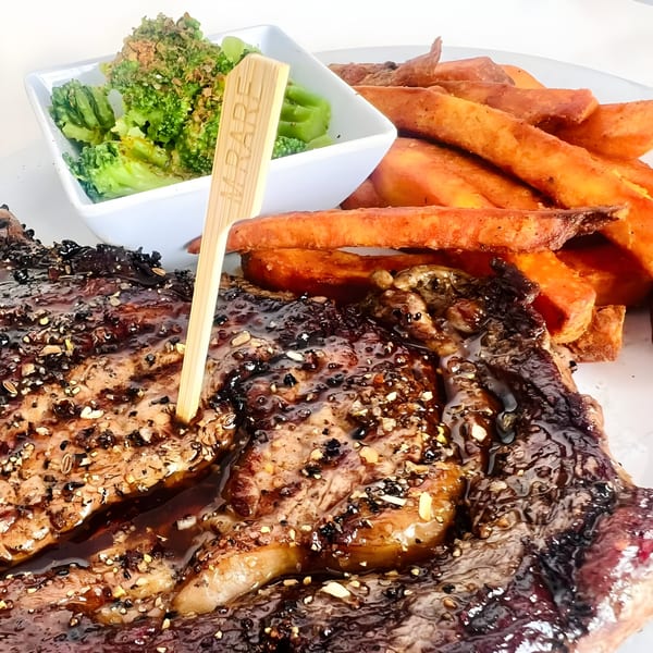 Grilled steak with a dark glaze, sweet potato fries, and a side of broccoli.