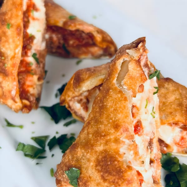 Crispy golden-brown Italian egg rolls filled with melted cheese and red sauce, garnished with parsley.